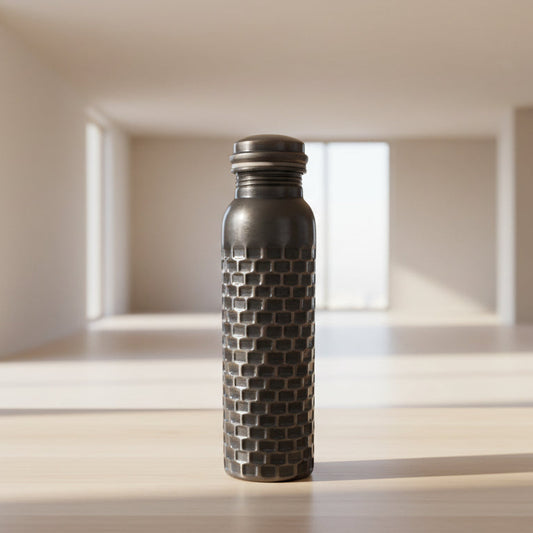 Decorative metal bottle with textured design on a tiled floor