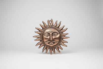 Bronze sun and moon wall art on a light gray wall