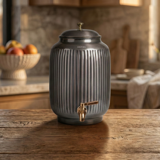 Dark gray drink dispenser with gold faucet on a wooden surface, kitchen setting.