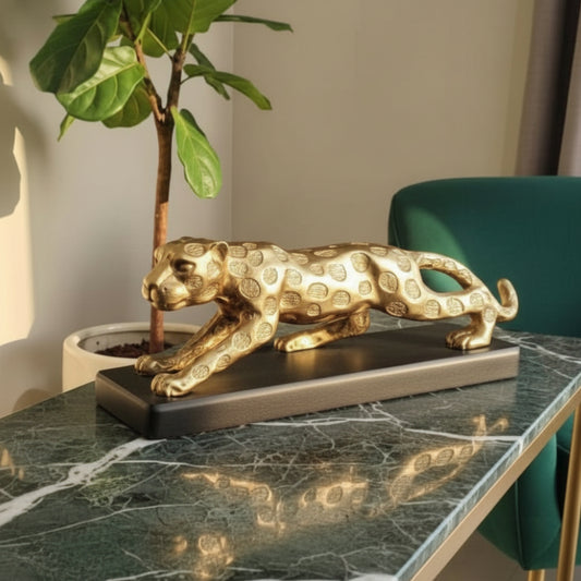 Gold panther statue on a marble table with a plant in the background