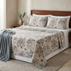 Bed with floral bedding and pillows in a bedroom setting